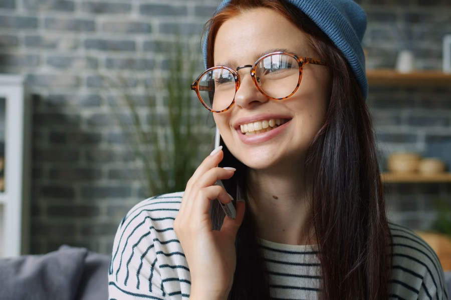Pessoa sorrindo enquanto conversa ao telefone em casa