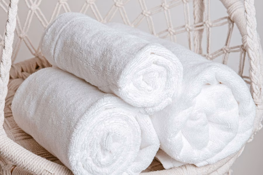 Toalhas brancas enroladas com delicadeza em tons claros